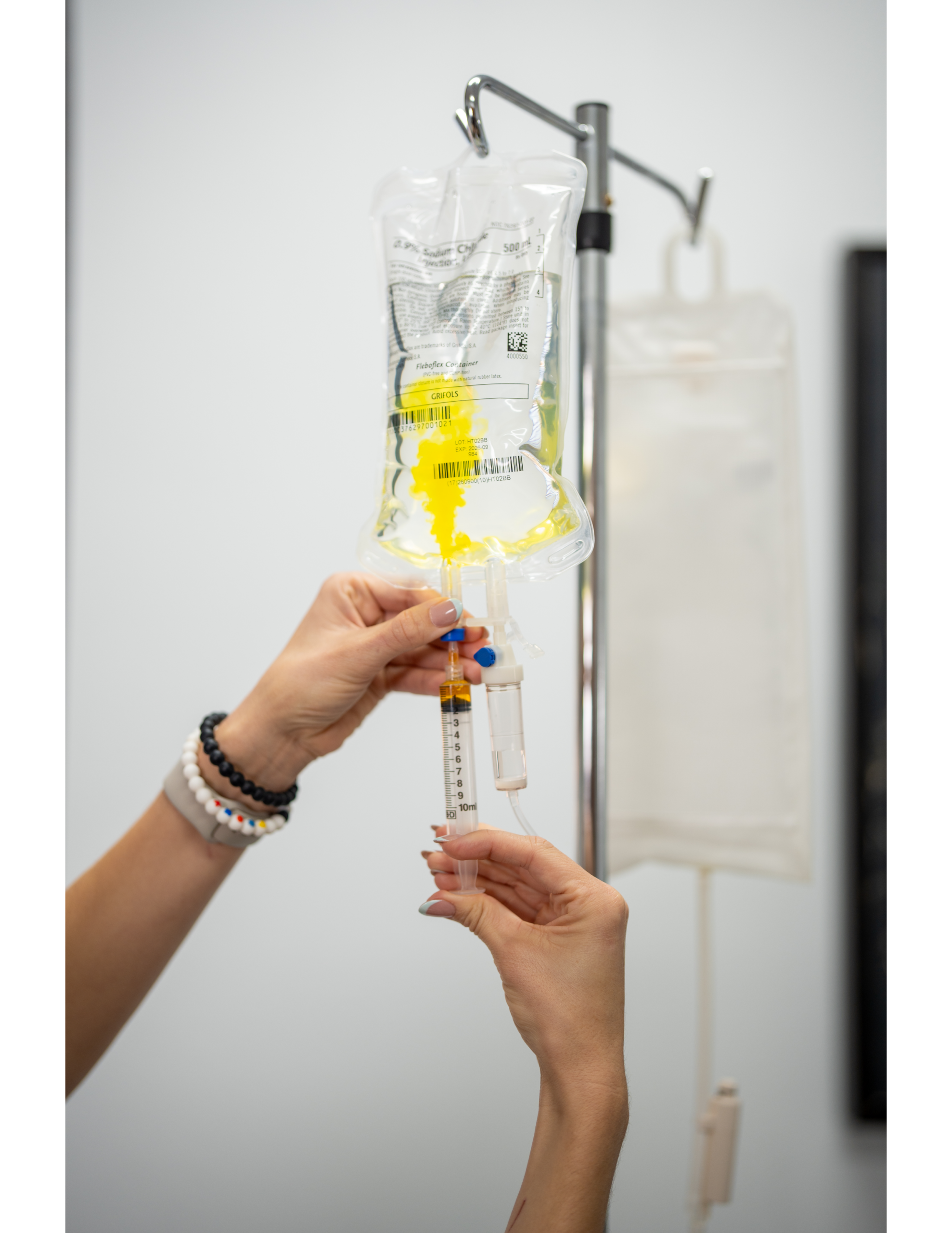 Hands drawing yellow fluid from IV bag
