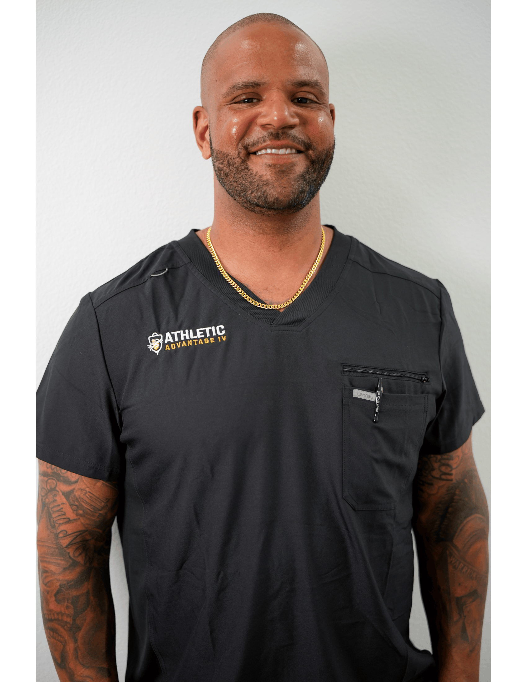 Smiling person in black medical scrubs, tattoos
